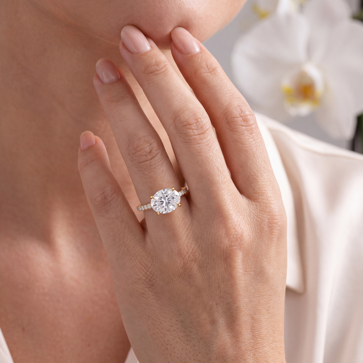 A model wearing an east-west oval moissanite ring in yellow gold on her hand.