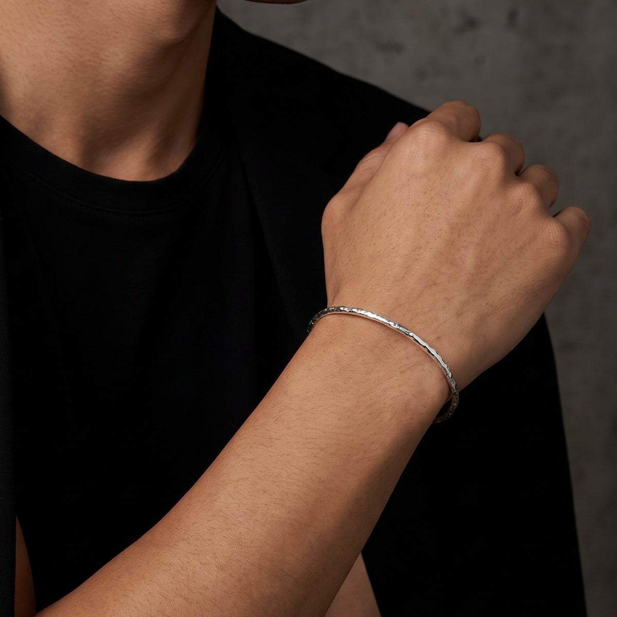 Close-up of a model wearing the slim hammered silver open cuff bracelet on a wrist.