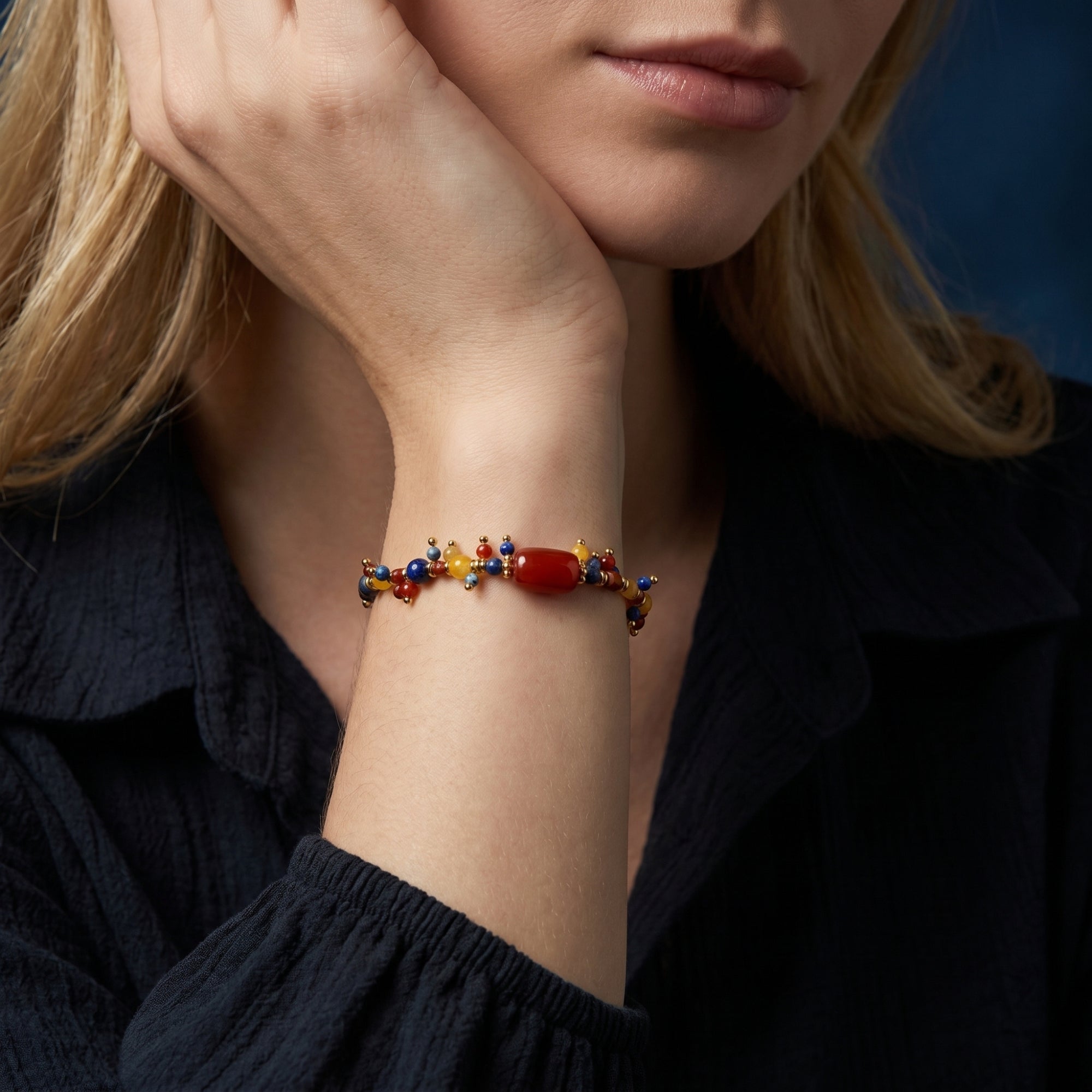Gold lapis lazuli and red gemstone bracelet worn on a woman's wrist for a lifestyle jewelry shot.