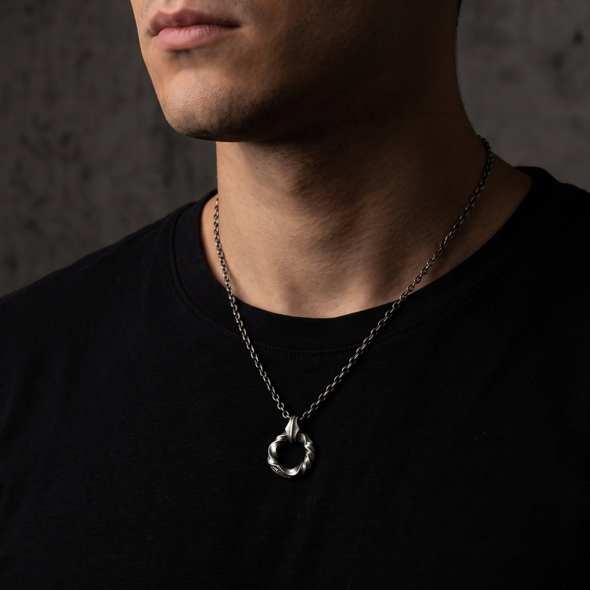 Model wearing the silver twisted circle pendant necklace over a plain black T-shirt.