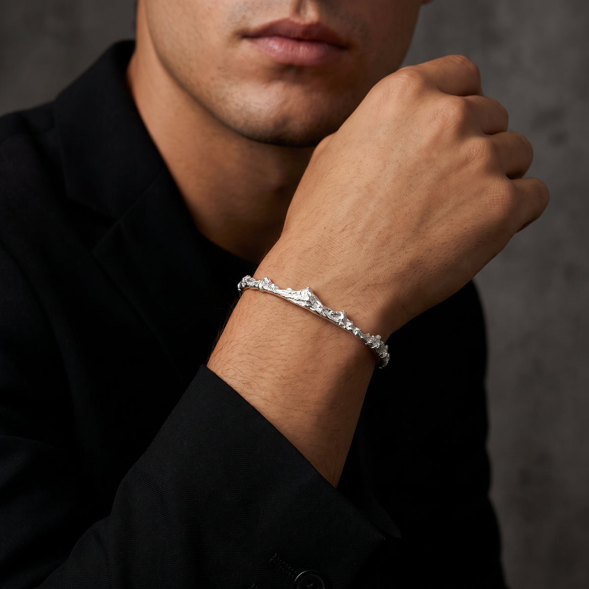 Model wearing a textured silver mountain ridge cuff bracelet with a black blazer.