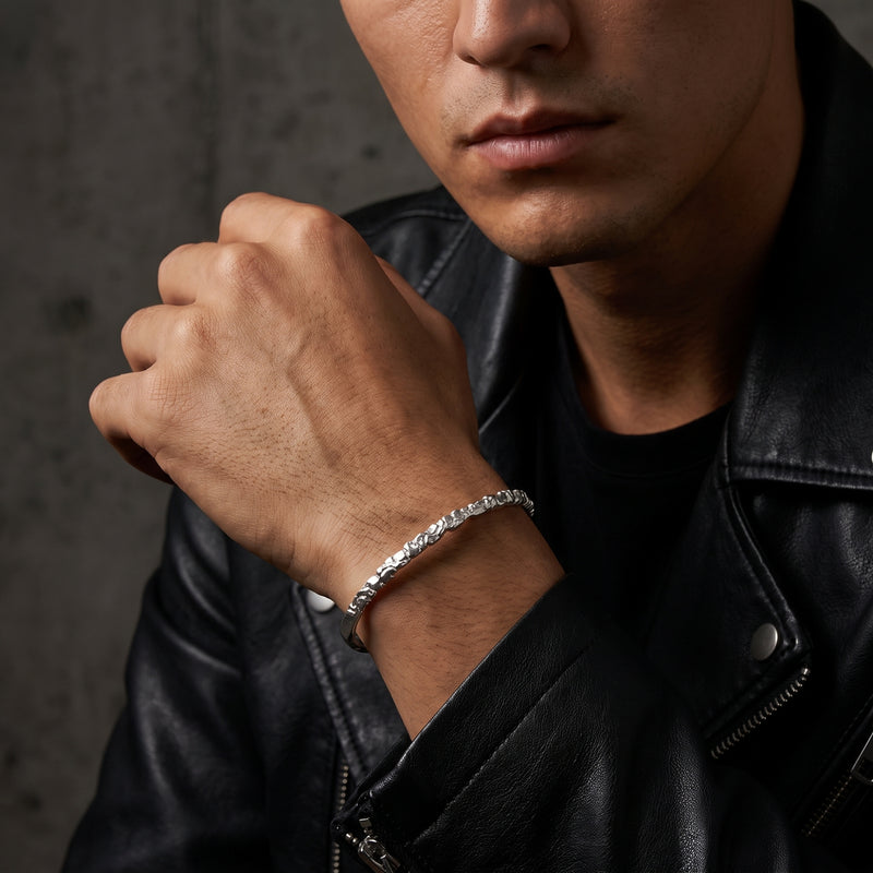Man in a black leather jacket wearing the carved silver ridge cuff bracelet near his chin.