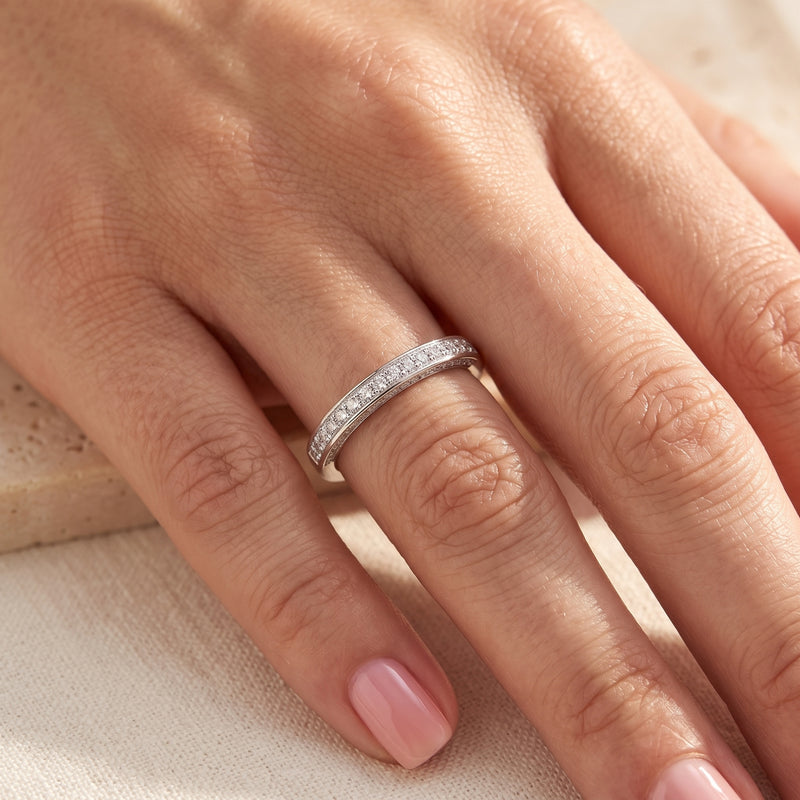 Double row pavé silver promise ring worn on a woman's finger.