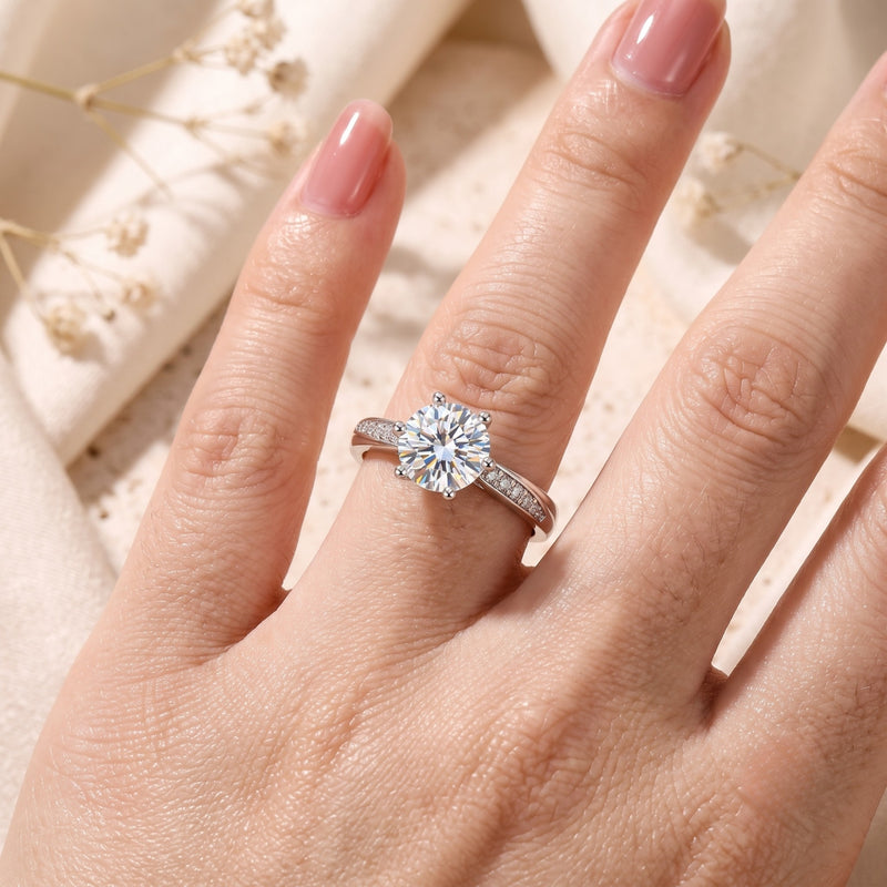 Round cut silver promise ring worn on a finger with pavé accents.