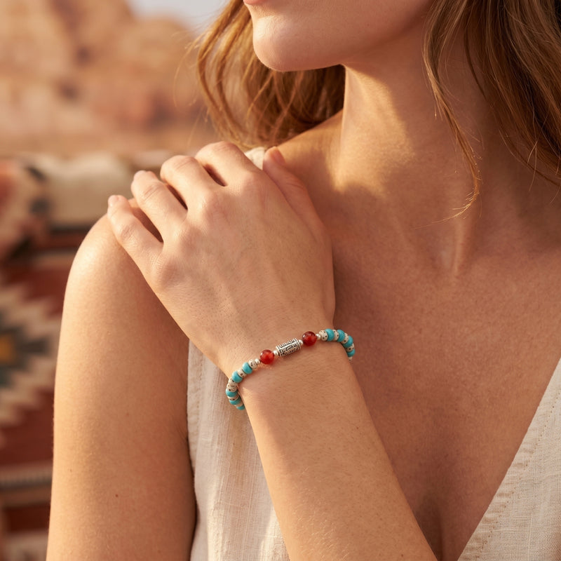 Woman wearing the turquoise beaded bracelet with carnelian accents and a silver mantra bead on her wrist.