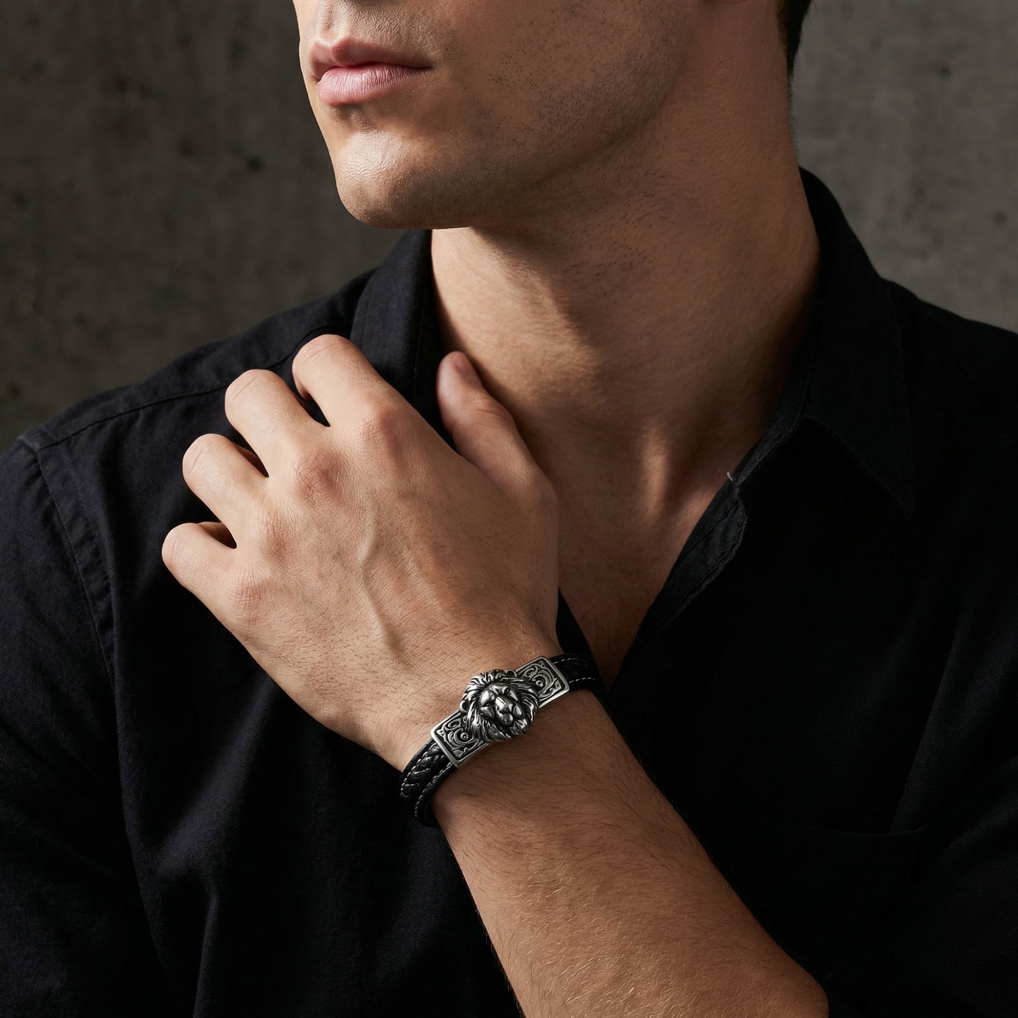 Leonidas braided black leather bracelet with a silver stainless steel lion head worn on a man's wrist.