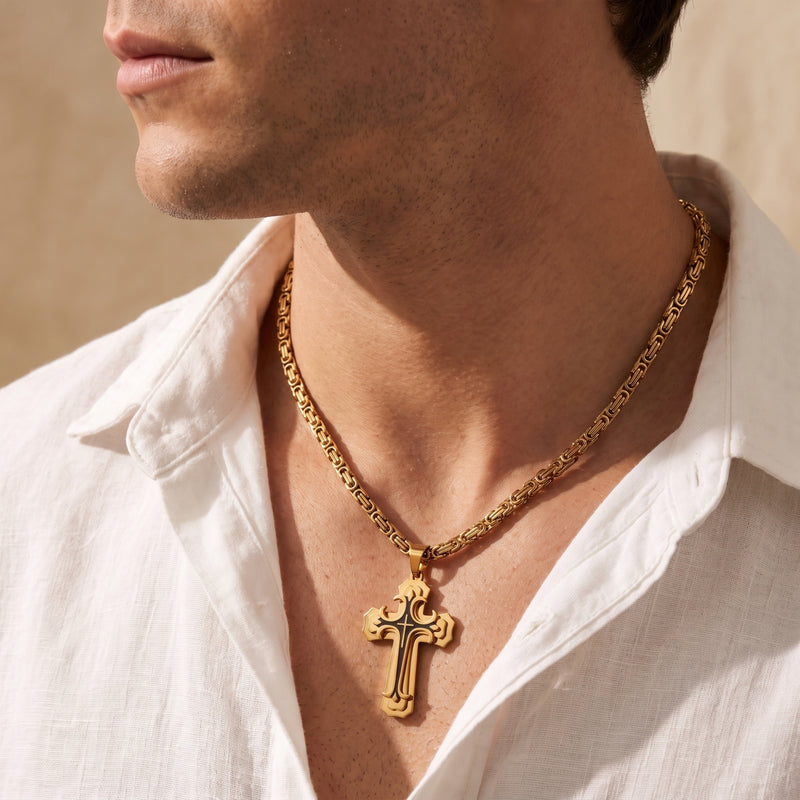 Side view of a man wearing a gold-toned ornate cross pendant necklace with a white collared shirt.