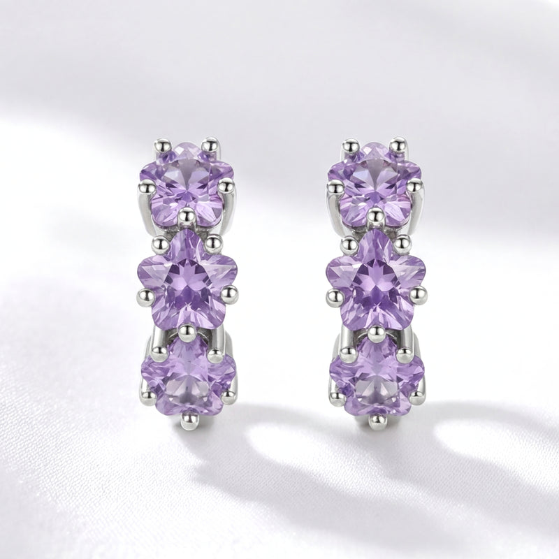 Front view of S925 sterling silver huggie earrings featuring triple star-cut purple simulated amethysts.