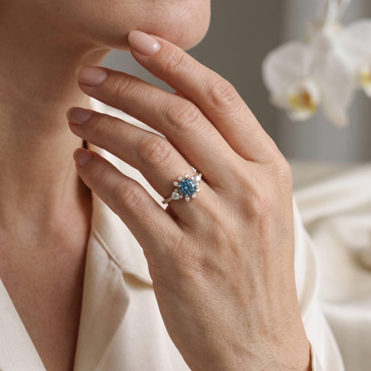 Model wearing a rose gold teal blue moissanite starburst halo ring resting near her chin.