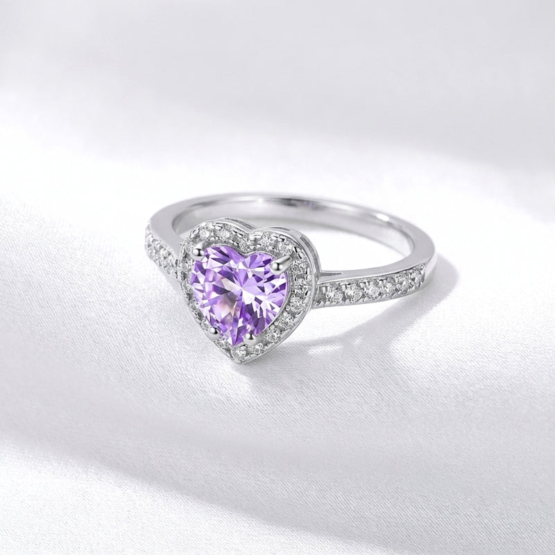 Side profile of the heart-cut purple amethyst S925 sterling silver ring resting on white silk-like fabric.