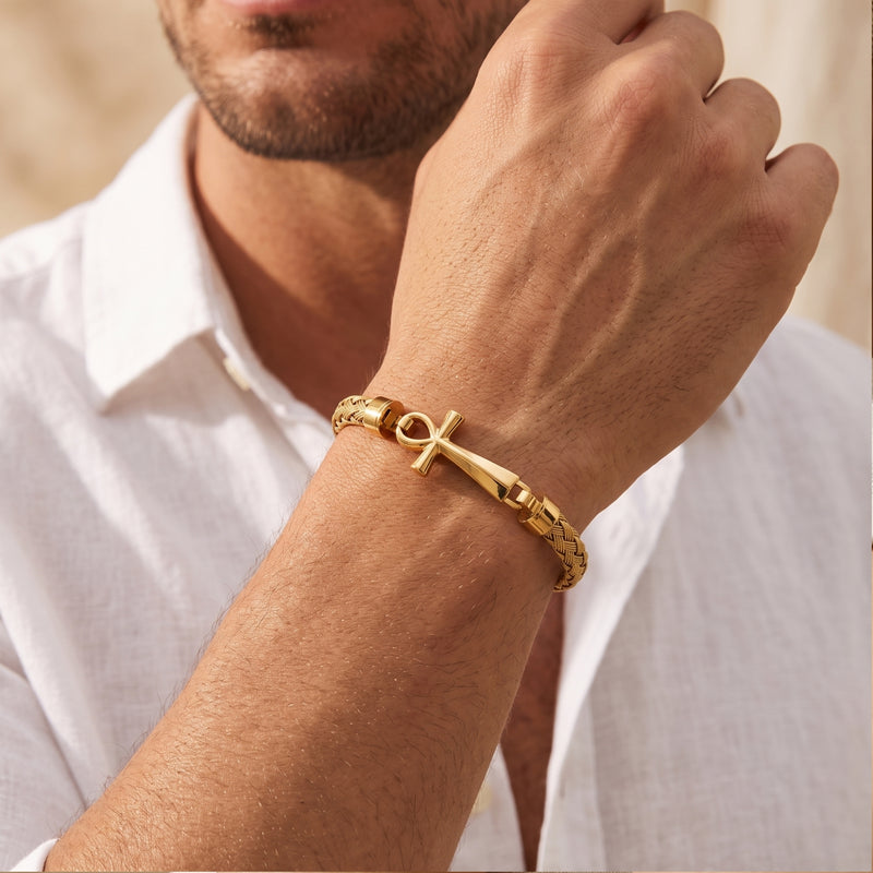 Close-up of a man wearing the gold-tone braided Ankh bracelet on his wrist with a white shirt.