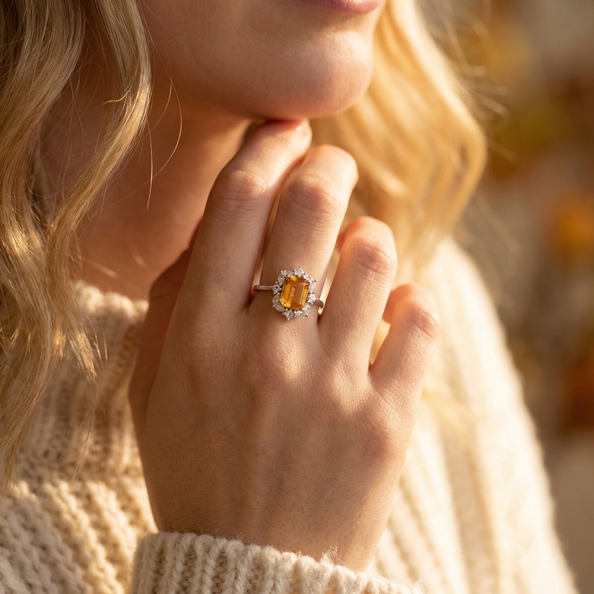 Model wearing a rectangular citrine halo ring in sterling silver, paired with a white knit sweater.