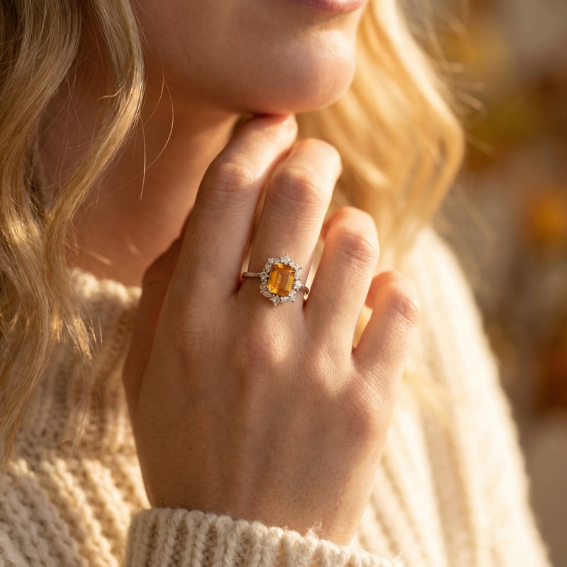 Model wearing a rectangular citrine halo ring in sterling silver, paired with a white knit sweater.