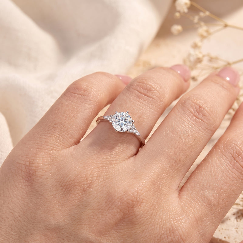 Round cut simulated diamond solitaire ring in sterling silver worn on a hand.