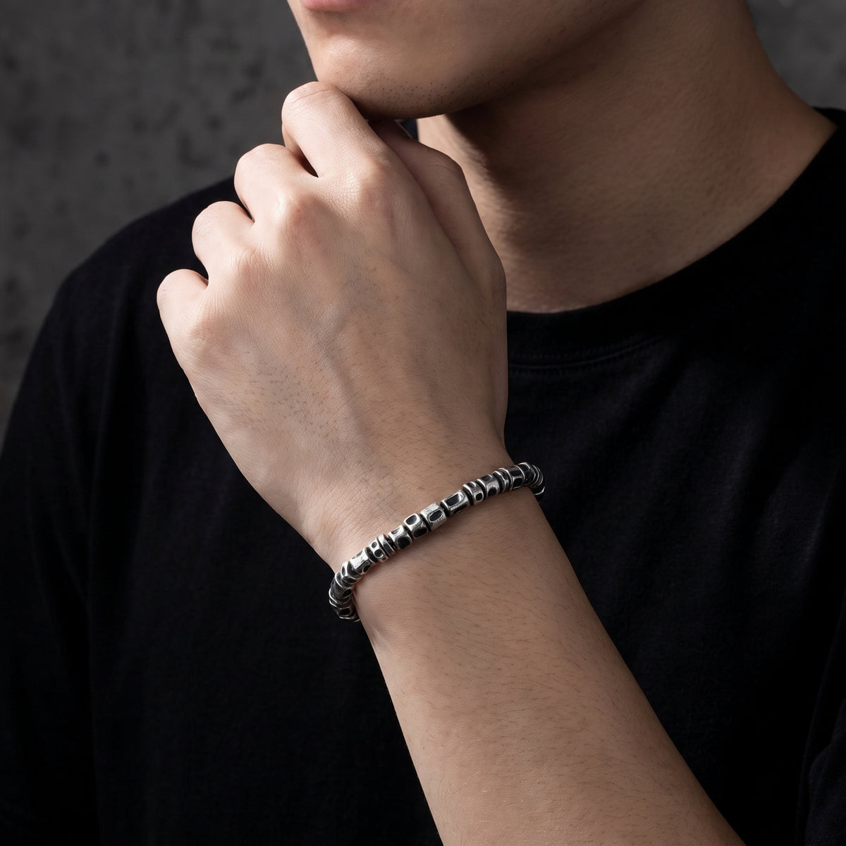 On-model view of the textured oxidized silver barrel bracelet worn on a wrist with a black shirt.
