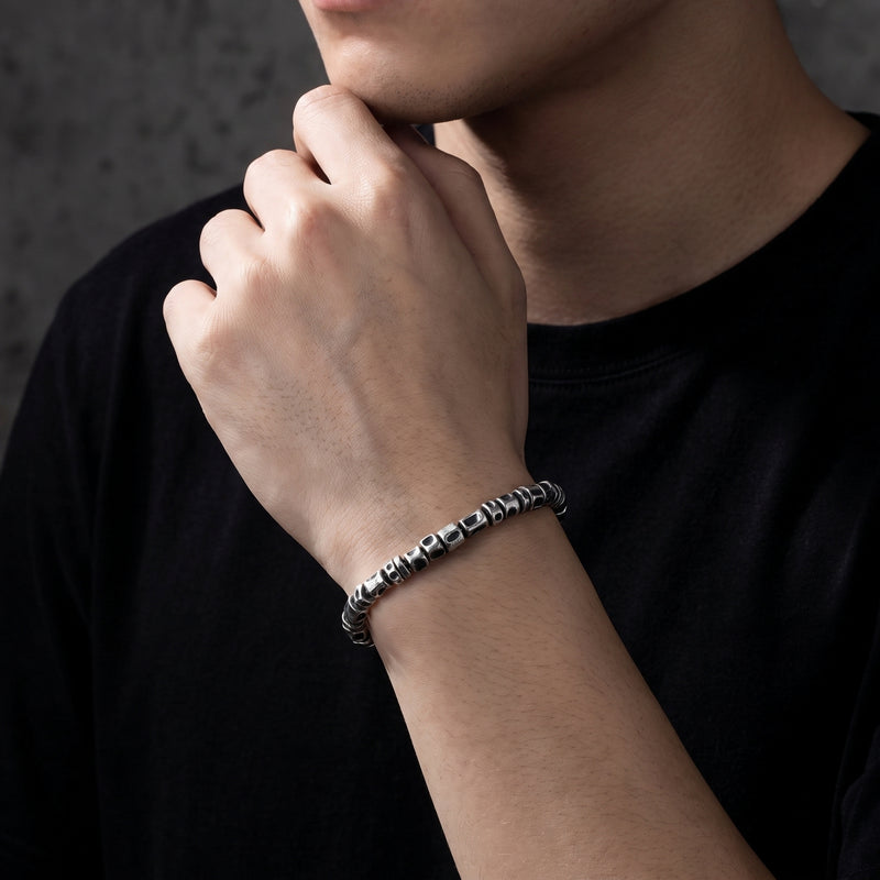 On-model view of the textured oxidized silver barrel bracelet worn on a wrist with a black shirt.