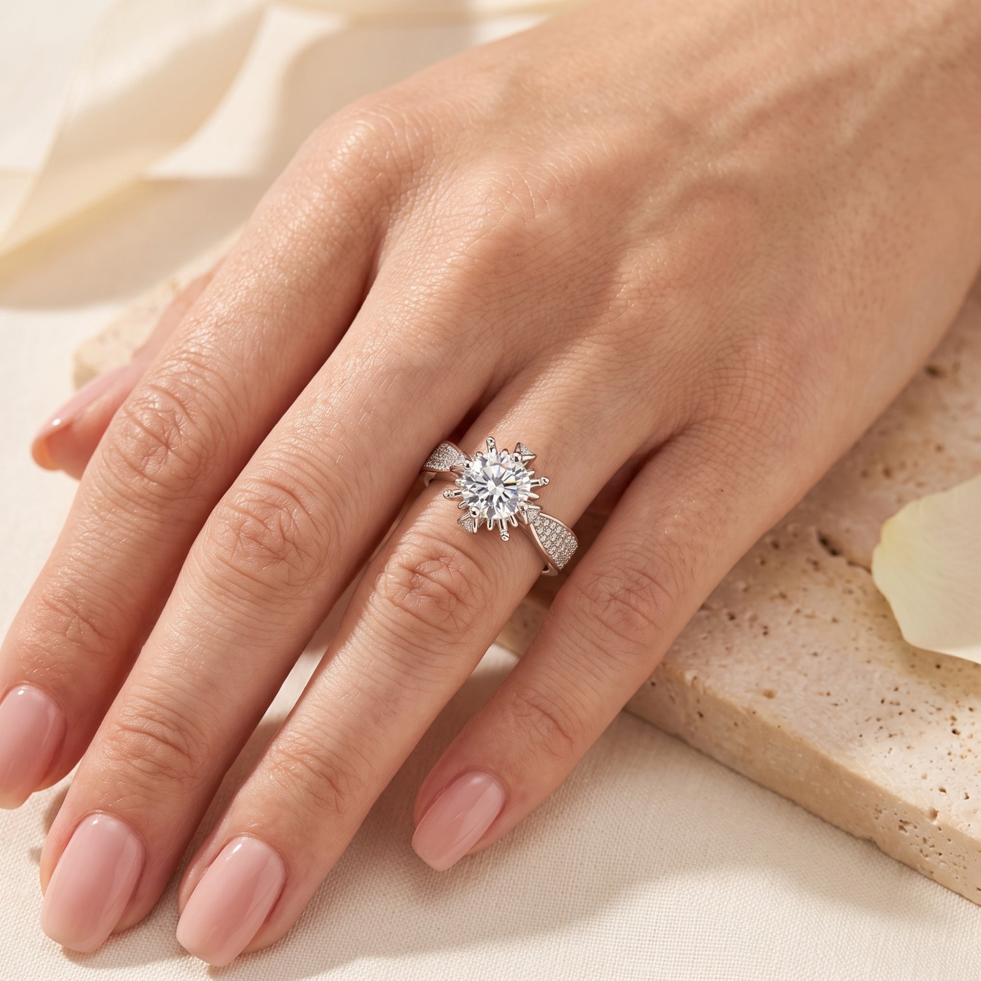 Round cut cubic zirconia starburst promise ring in silver worn on a woman's hand.