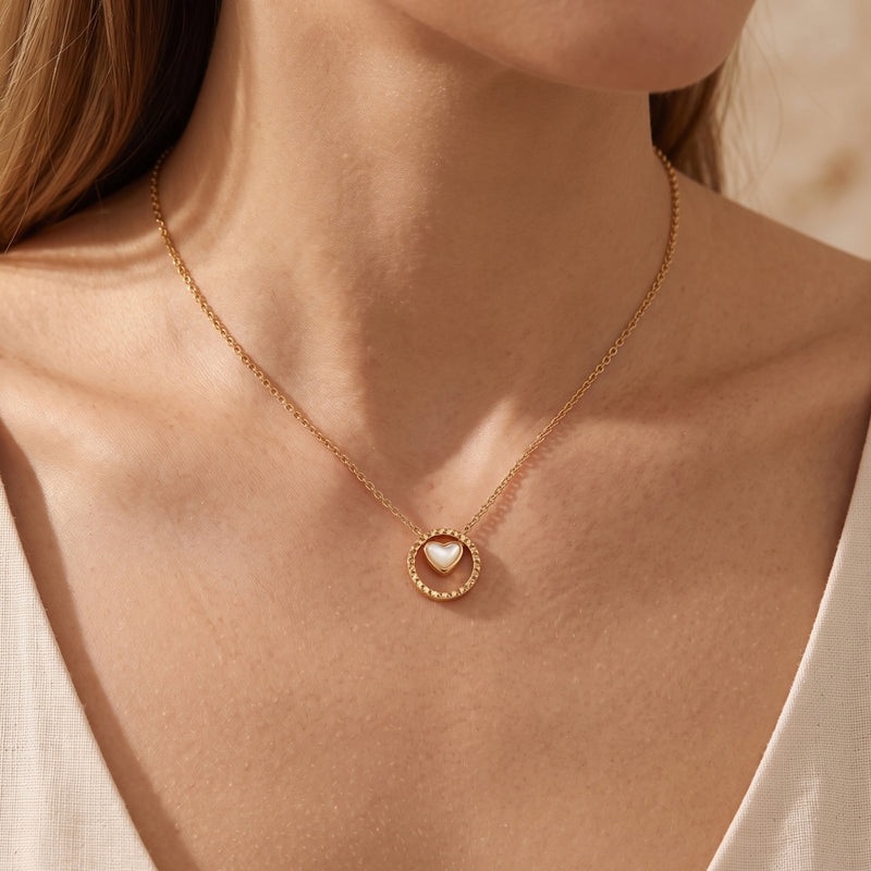 Model wearing gold Rosetta necklace with heart-shaped mother of pearl pendant in textured frame.