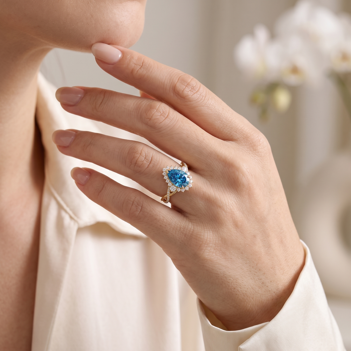 Model wearing a pear cut blue moissanite halo engagement ring with an intertwined band in rose gold.