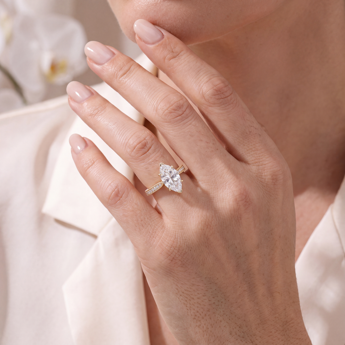 Close-up of a model wearing a yellow gold marquise moissanite engagement ring on her hand.