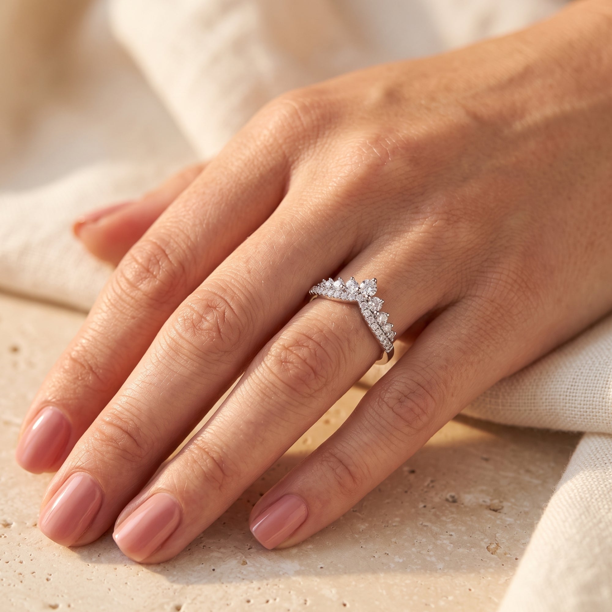 Double-row silver chevron ring with cascading cubic zirconia worn on a woman's hand.