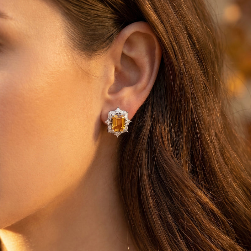 Model wearing an emerald cut natural citrine stud earring with a diamond halo in white gold.