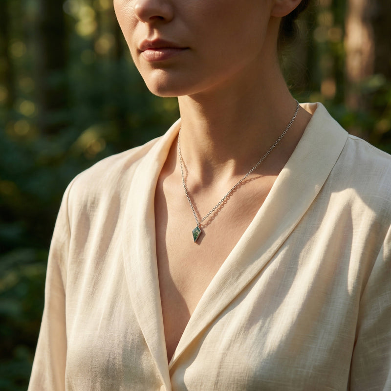 Model wearing the kite cut moss agate pendant necklace in S925 sterling silver against a soft forest background.