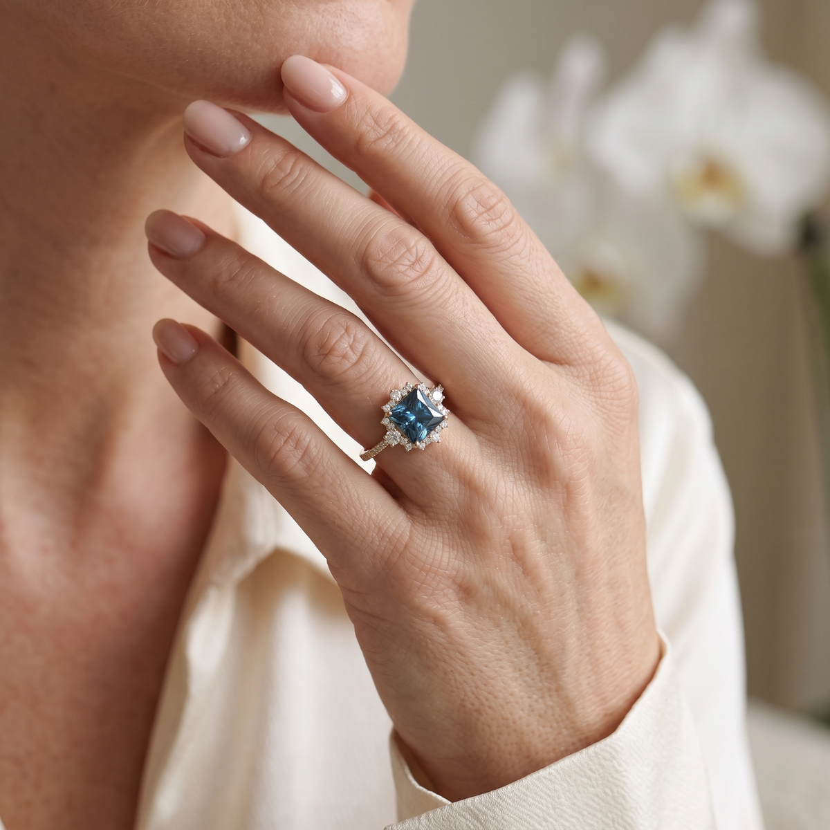 Princess cut blue gemstone engagement ring in rose gold worn on a hand.