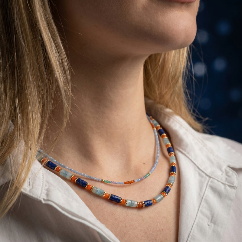 Model wearing the Cobalt Strands layered gold necklace featuring natural lapis and multi-color gemstone beads.