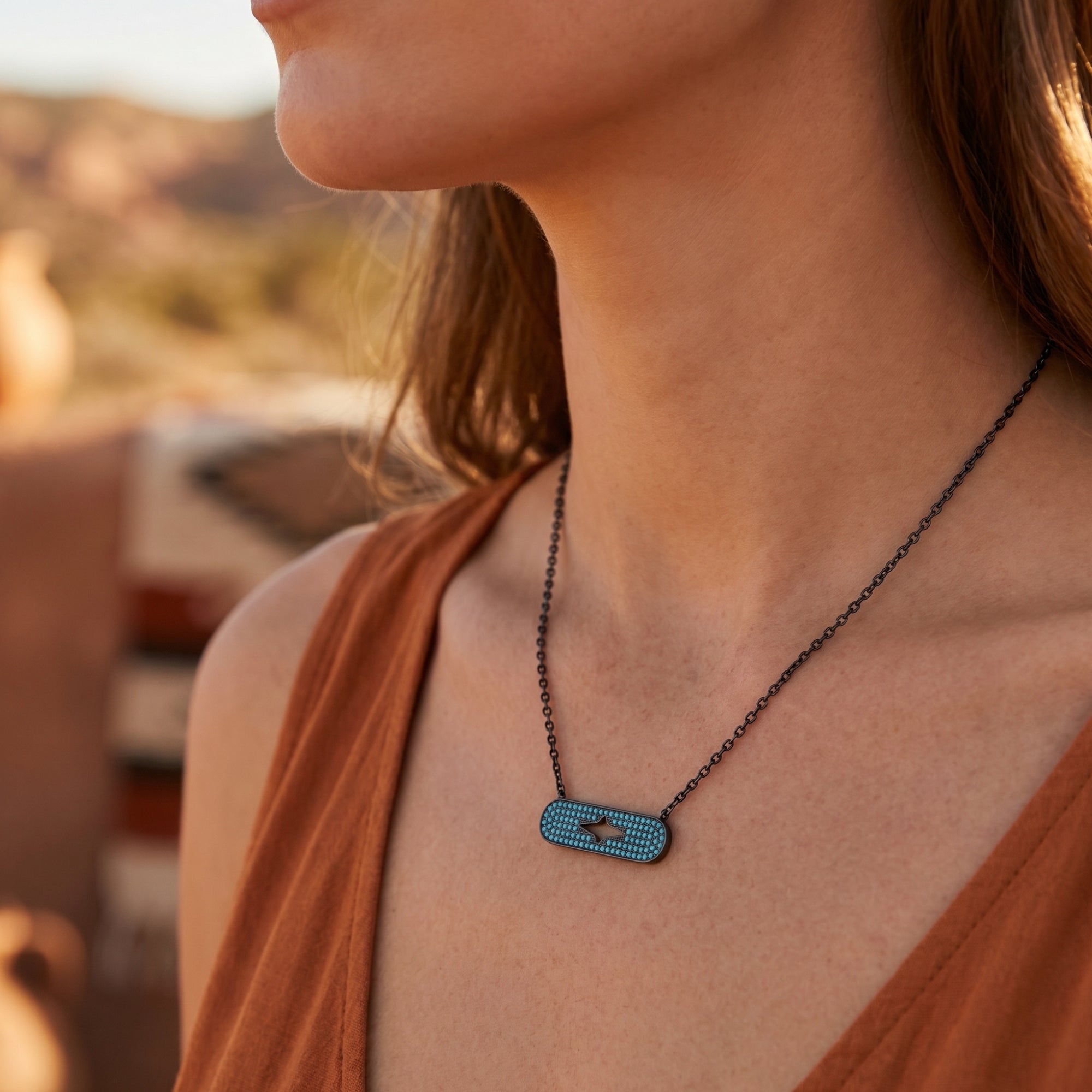 Woman wearing the Chaco turquoise bar necklace in sterling silver against a desert landscape background.