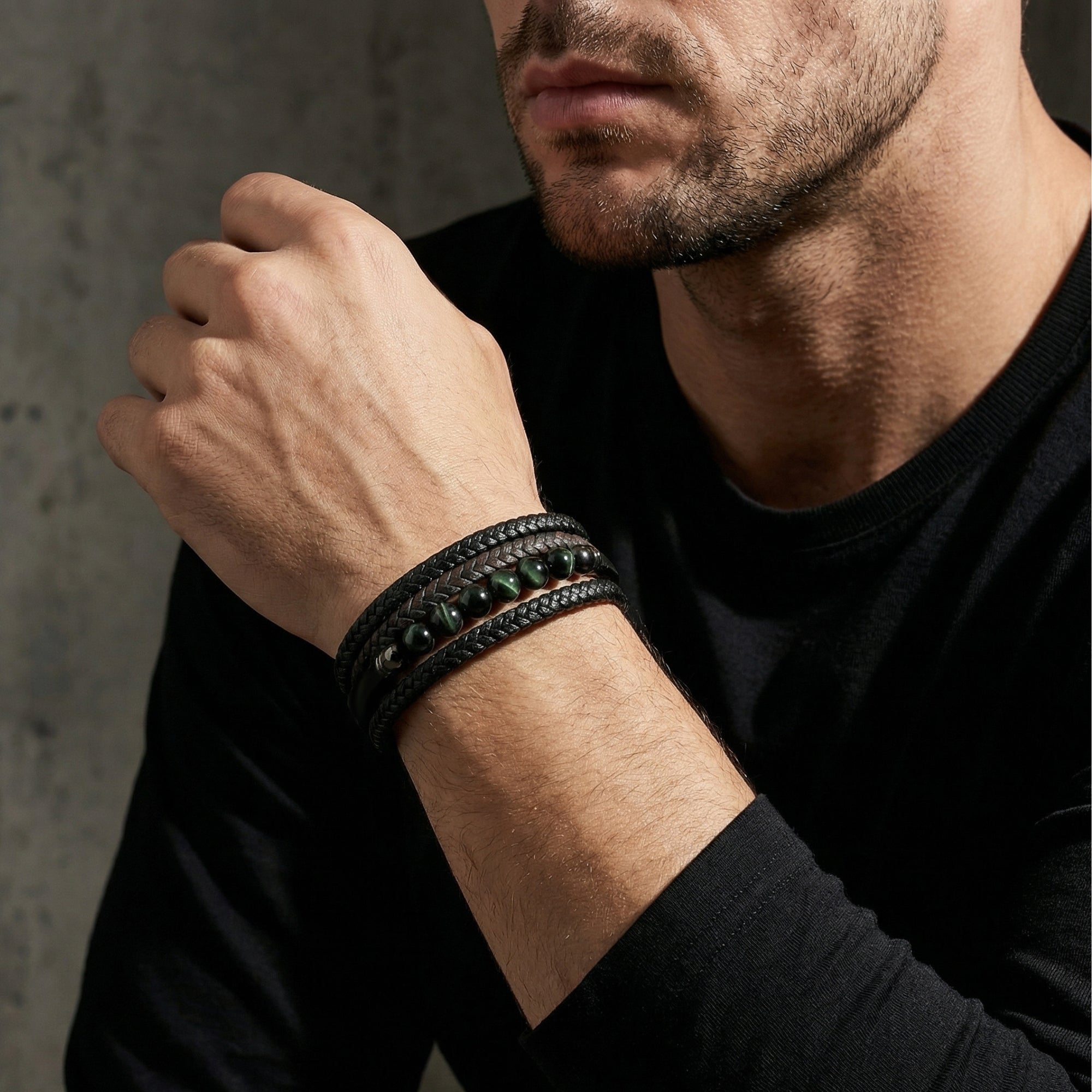 Men's multi-strand braided leather bracelet with round green stones worn on a wrist.