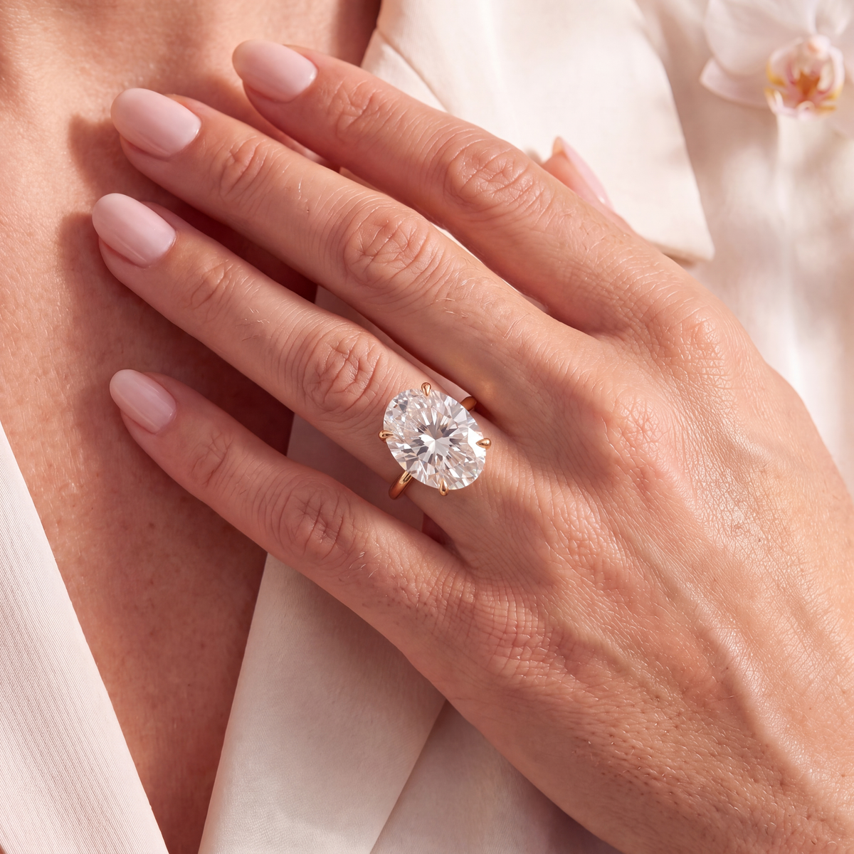 Woman wearing an oval moissanite solitaire engagement ring in yellow gold on her hand.