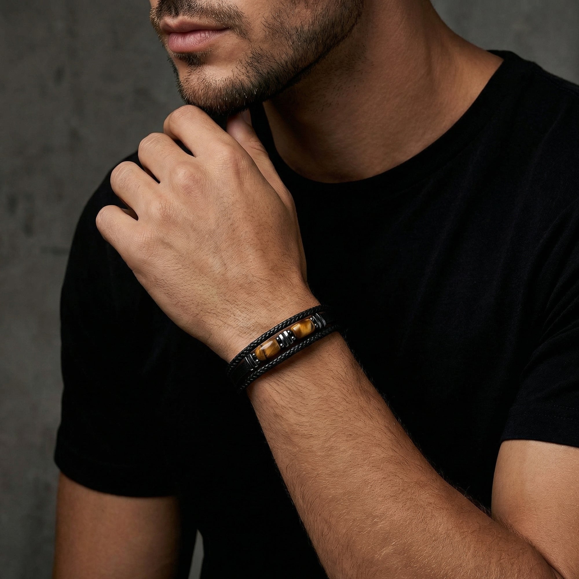 Men's black leather Tiger's Eye bracelet with black stainless steel accents worn on a model's wrist.