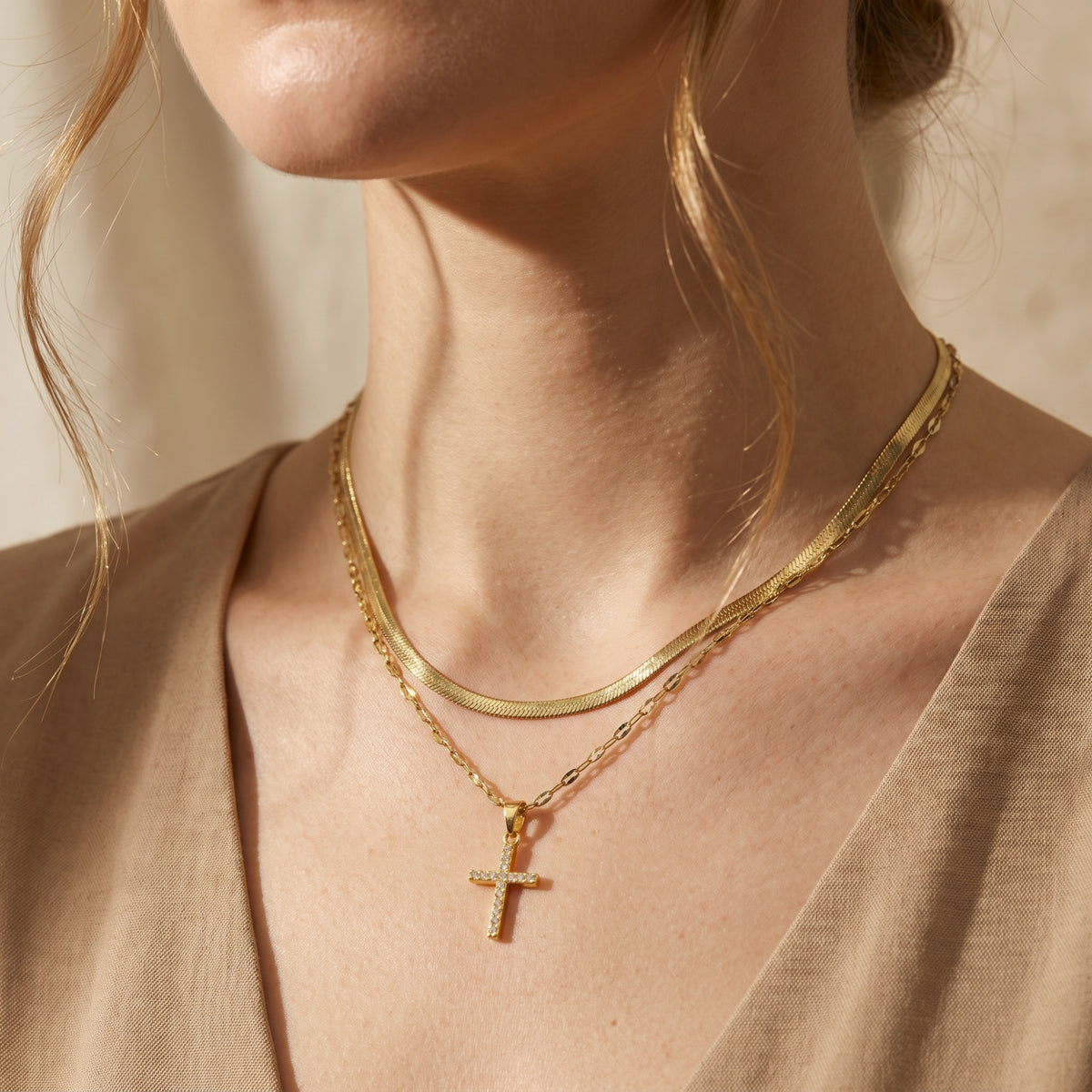 Front view of model wearing the gold-tone layered cross necklace with a flat snake chain and cross pendant.