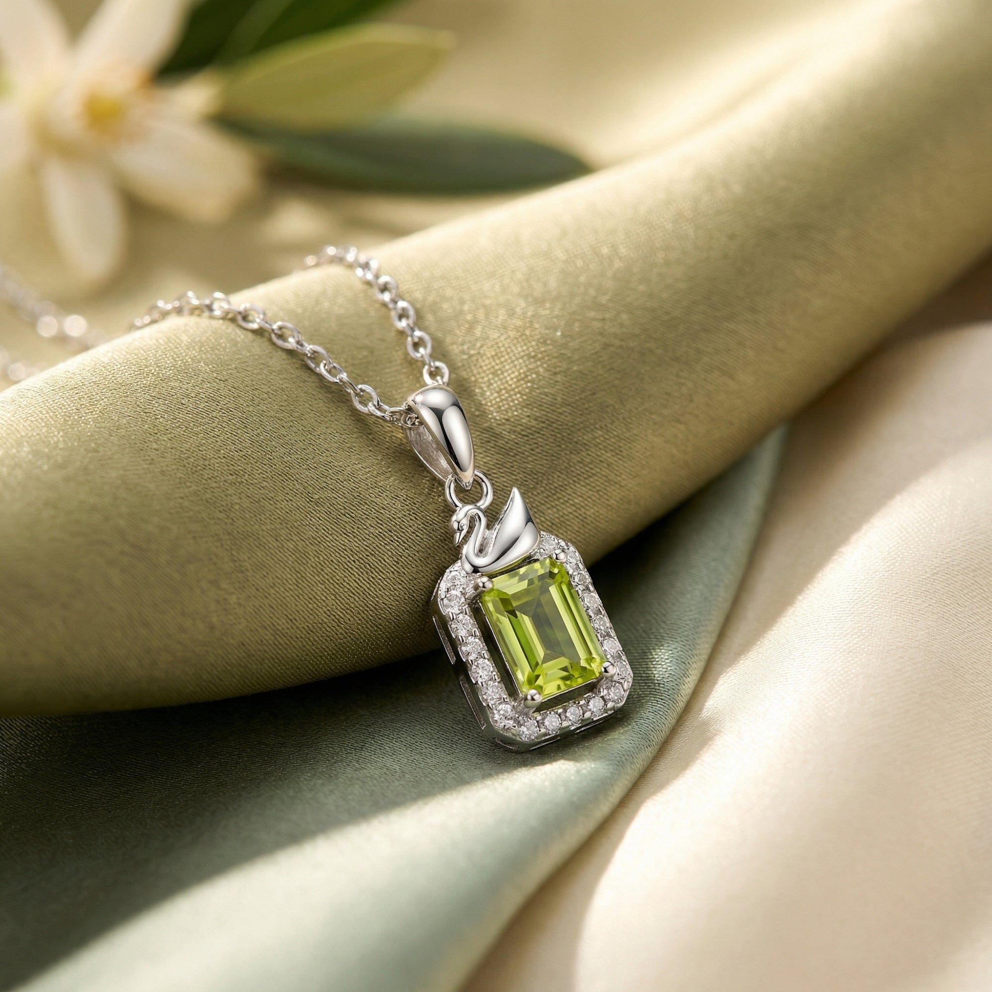Close-up of an emerald-cut natural peridot pendant with a diamond-like halo and swan bail in S925 sterling silver.