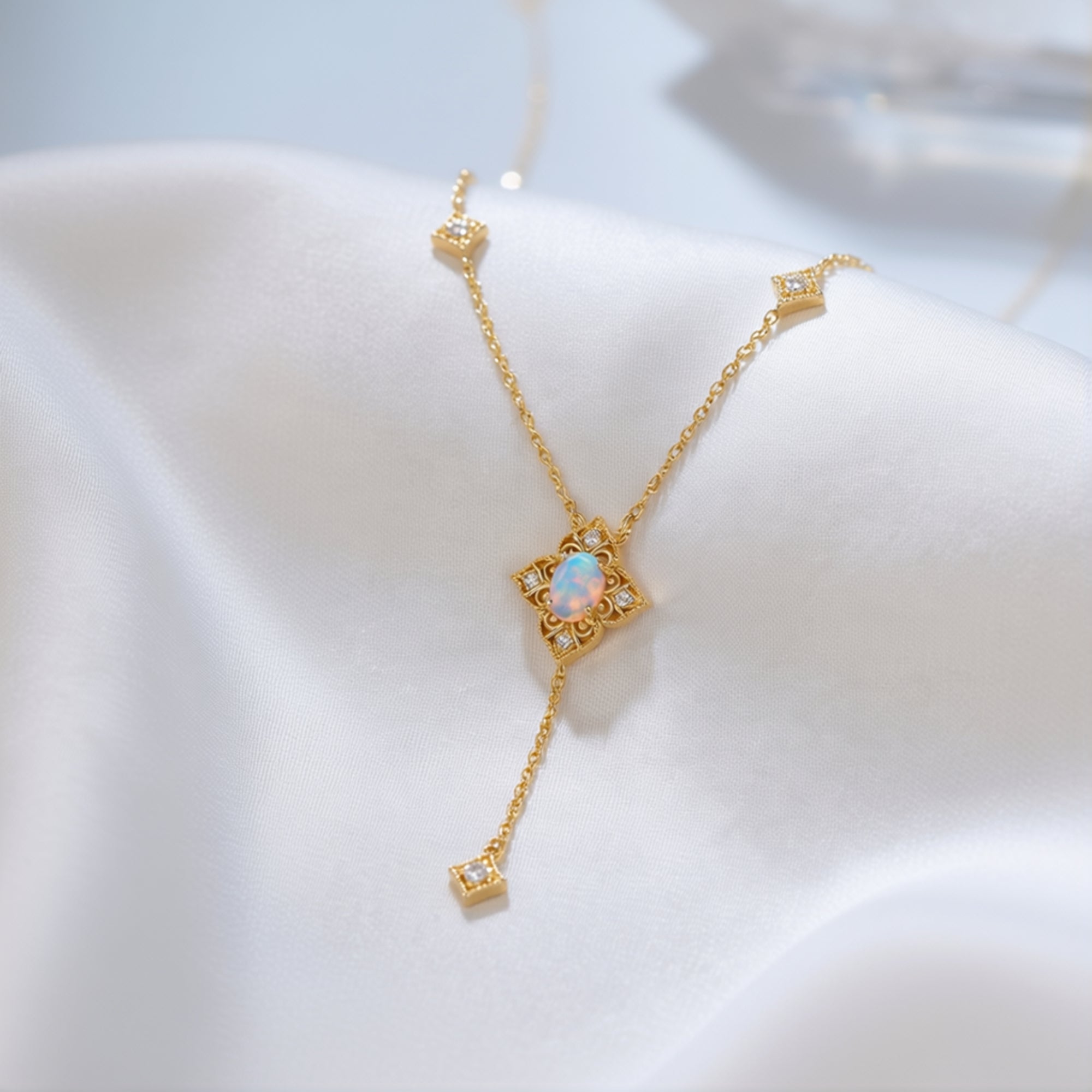 Detailed view of the gold-tone lariat necklace's intricate setting and oval white opal gemstone.