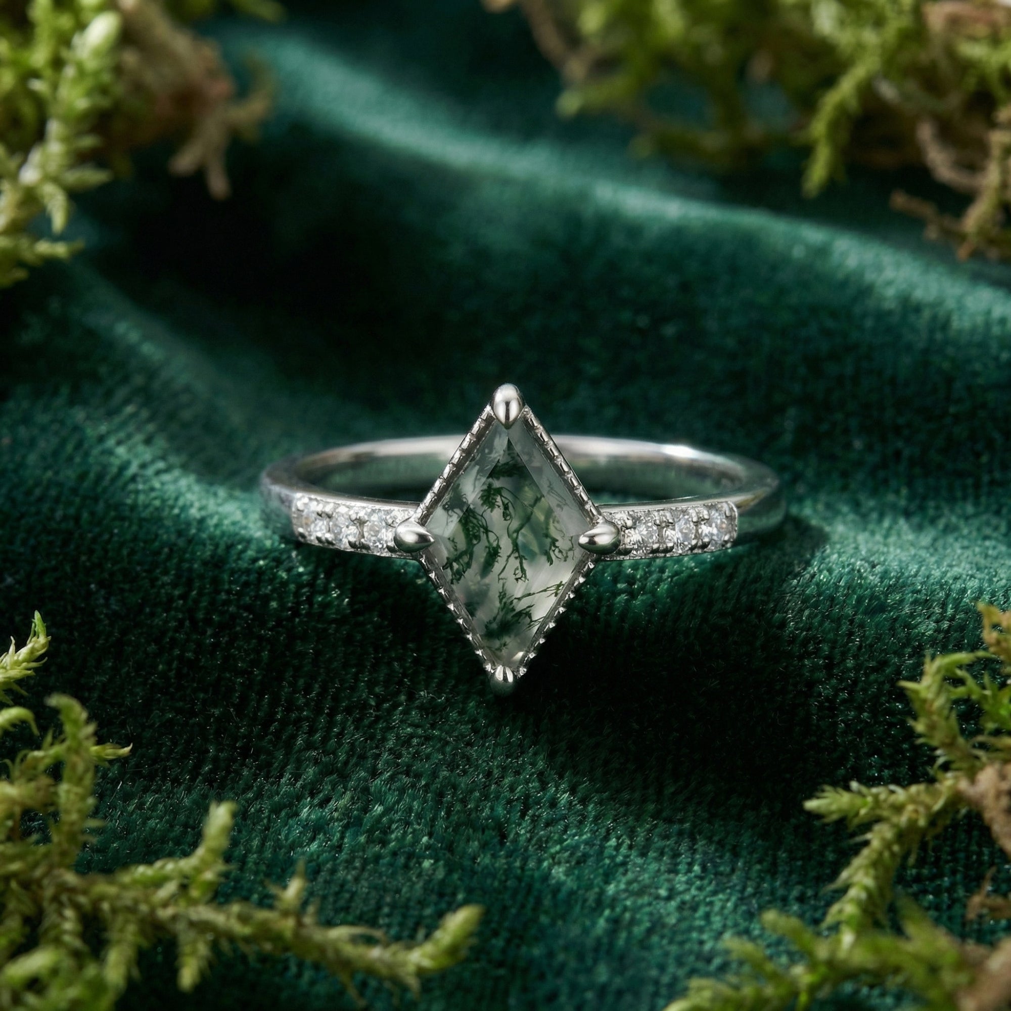 Macro view of a kite cut natural moss agate stone and channel set diamonds in a sterling silver ring setting.