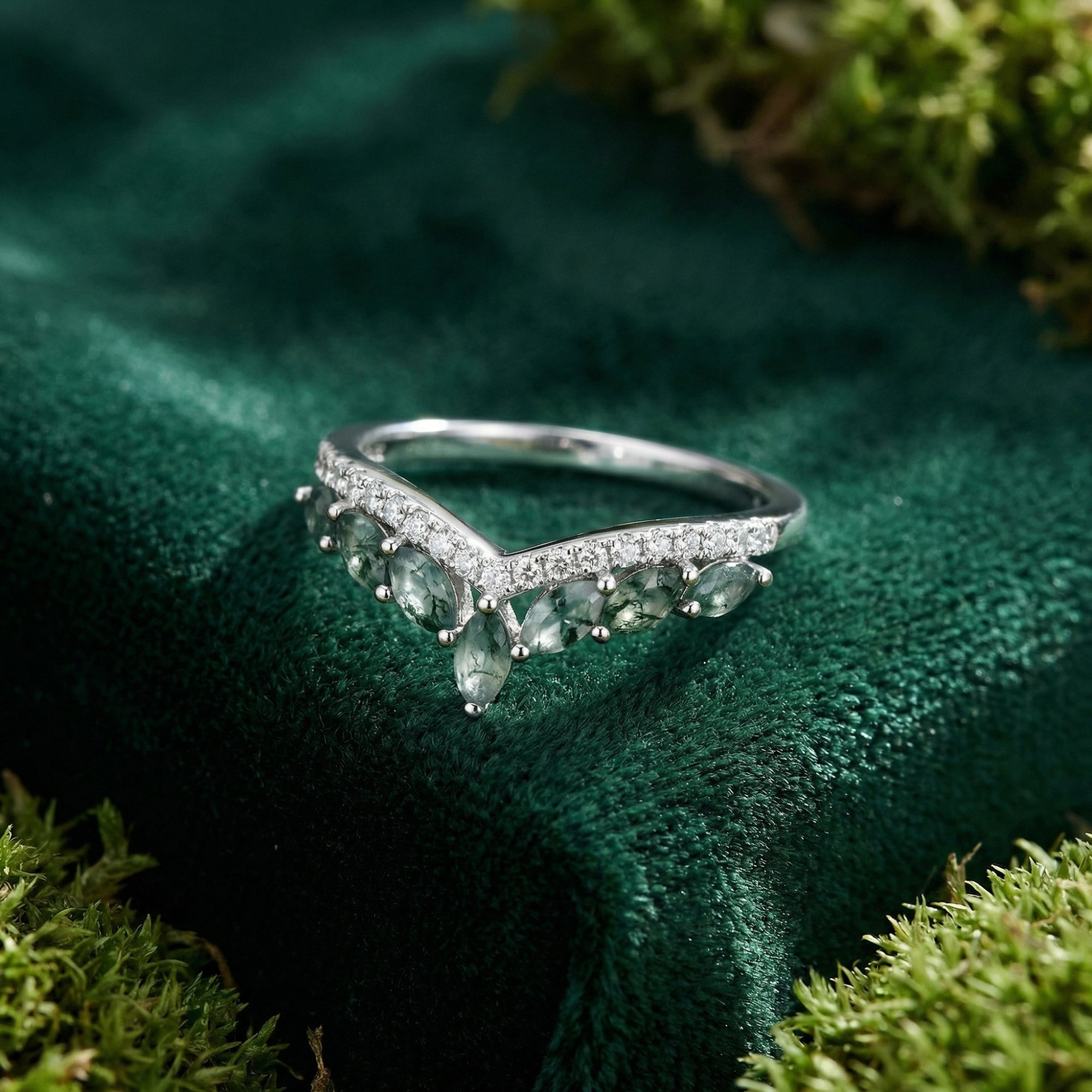Front view of the sterling silver wave ring with marquise moss agate stones on a dark green velvet and moss surface.