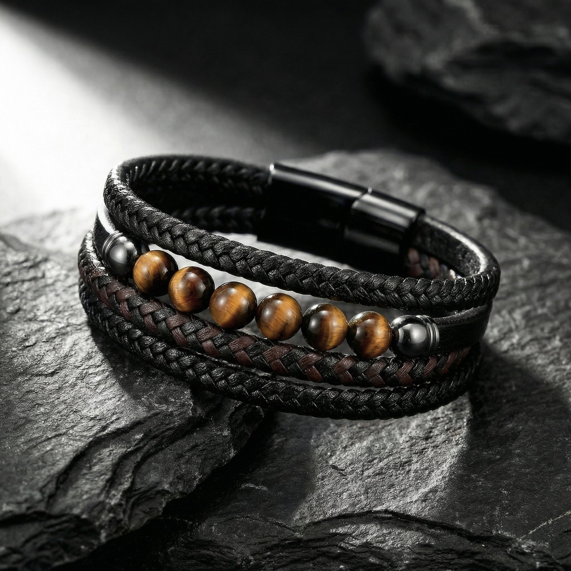 Garrison multi-strand black leather bracelet with round tiger's eye beads and black steel clasp on slate.