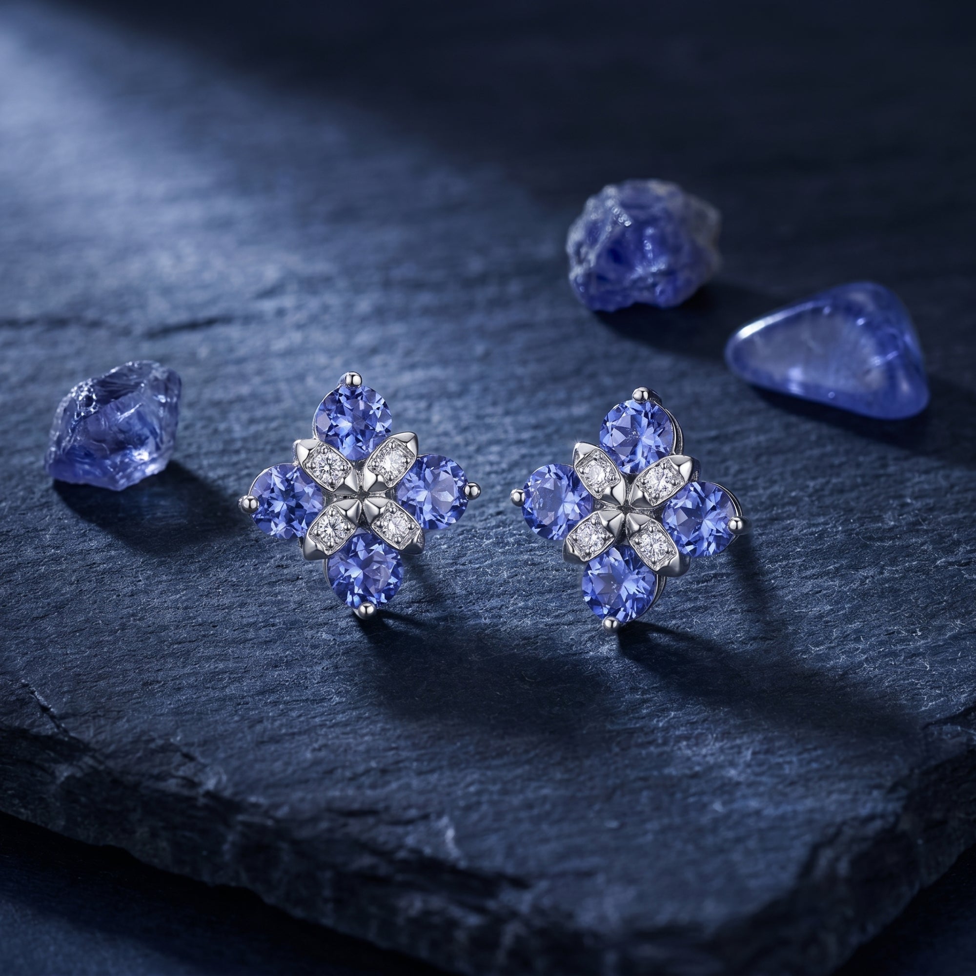 Pair of round tanzanite flower cluster earrings in white gold on a textured slate background.