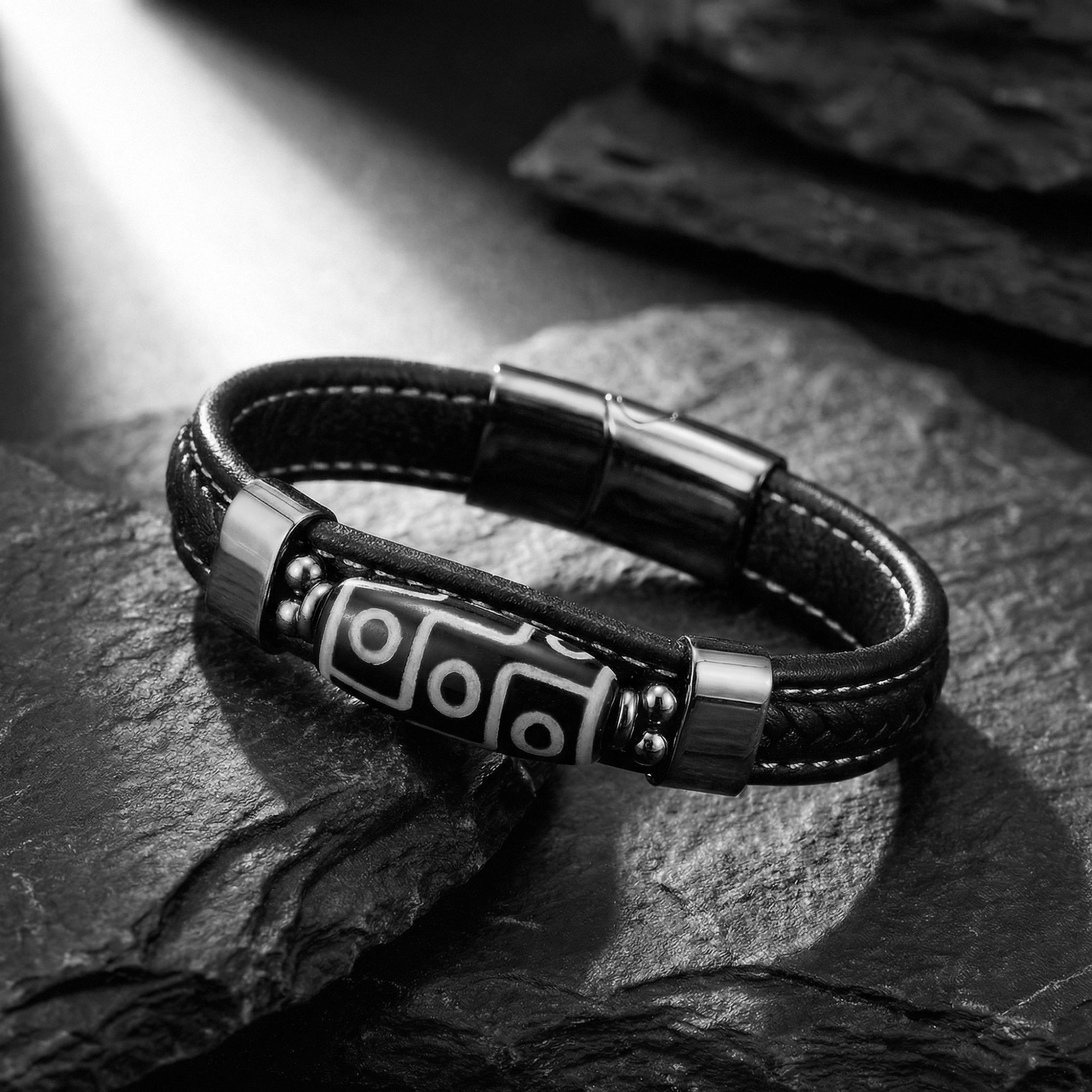 Close-up of the magnetic clasp and silver-tone 316L stainless steel geometric centerpiece on a black leather bracelet.