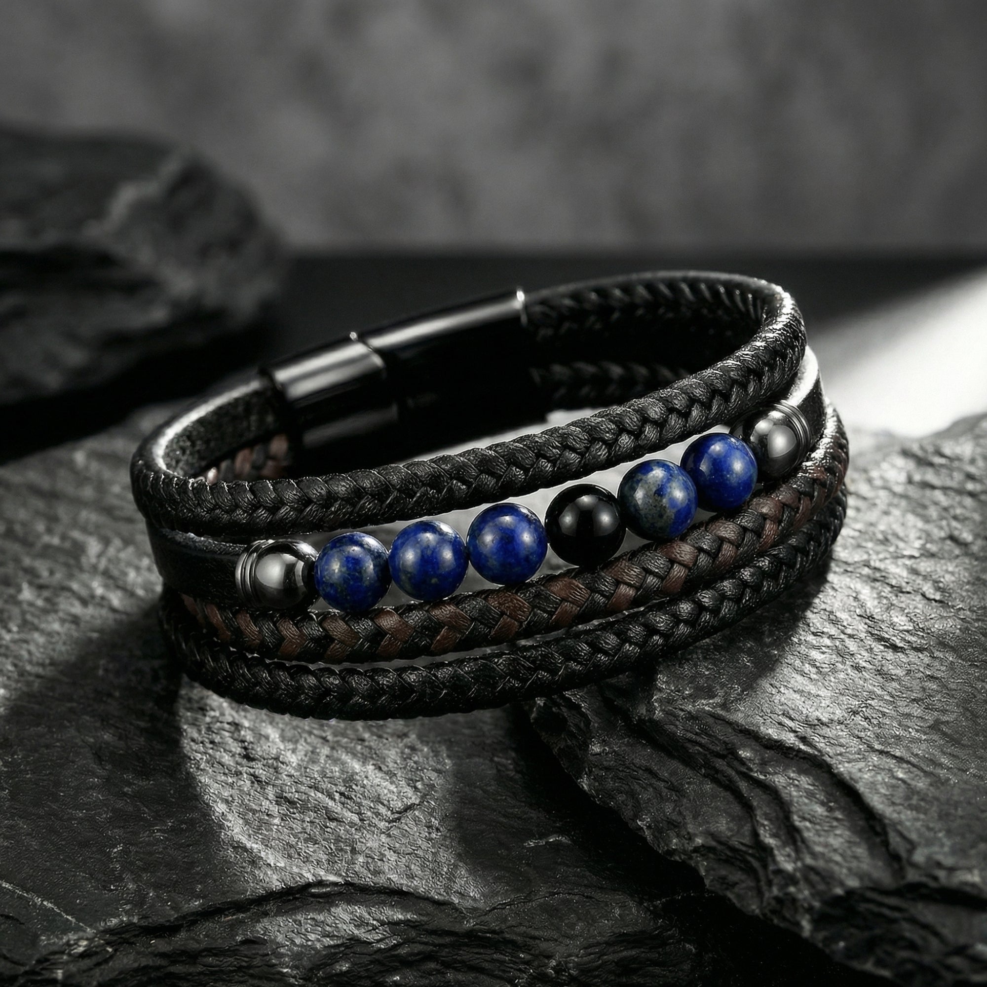 Close-up of blue lapis beads and black braided leather on a multi-strand men's bracelet with a black steel clasp.