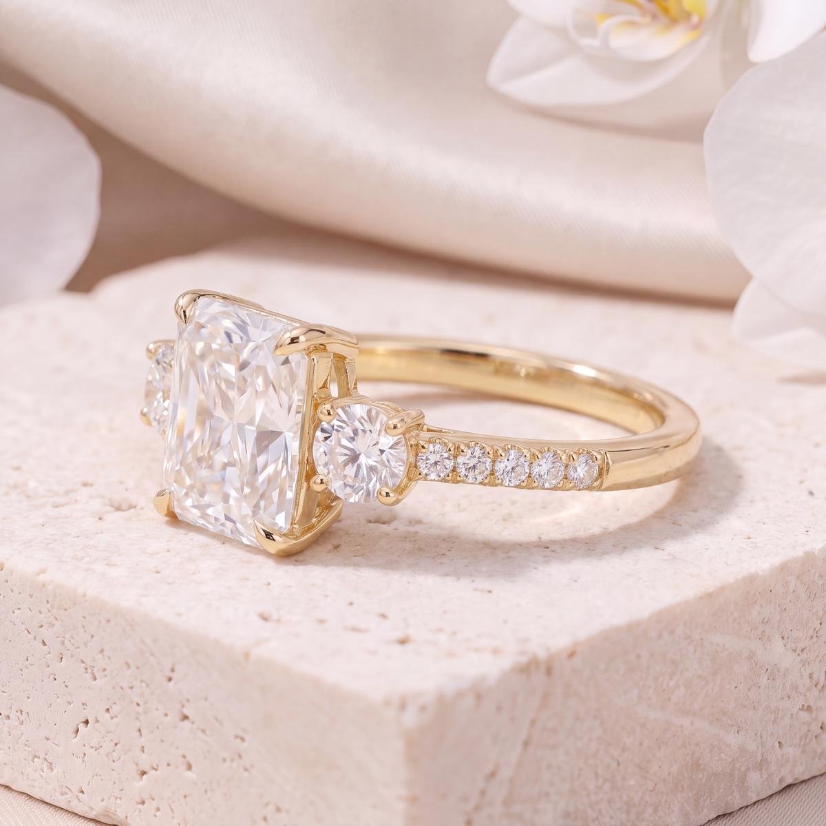 Side view of a yellow gold radiant cut moissanite three-stone ring.