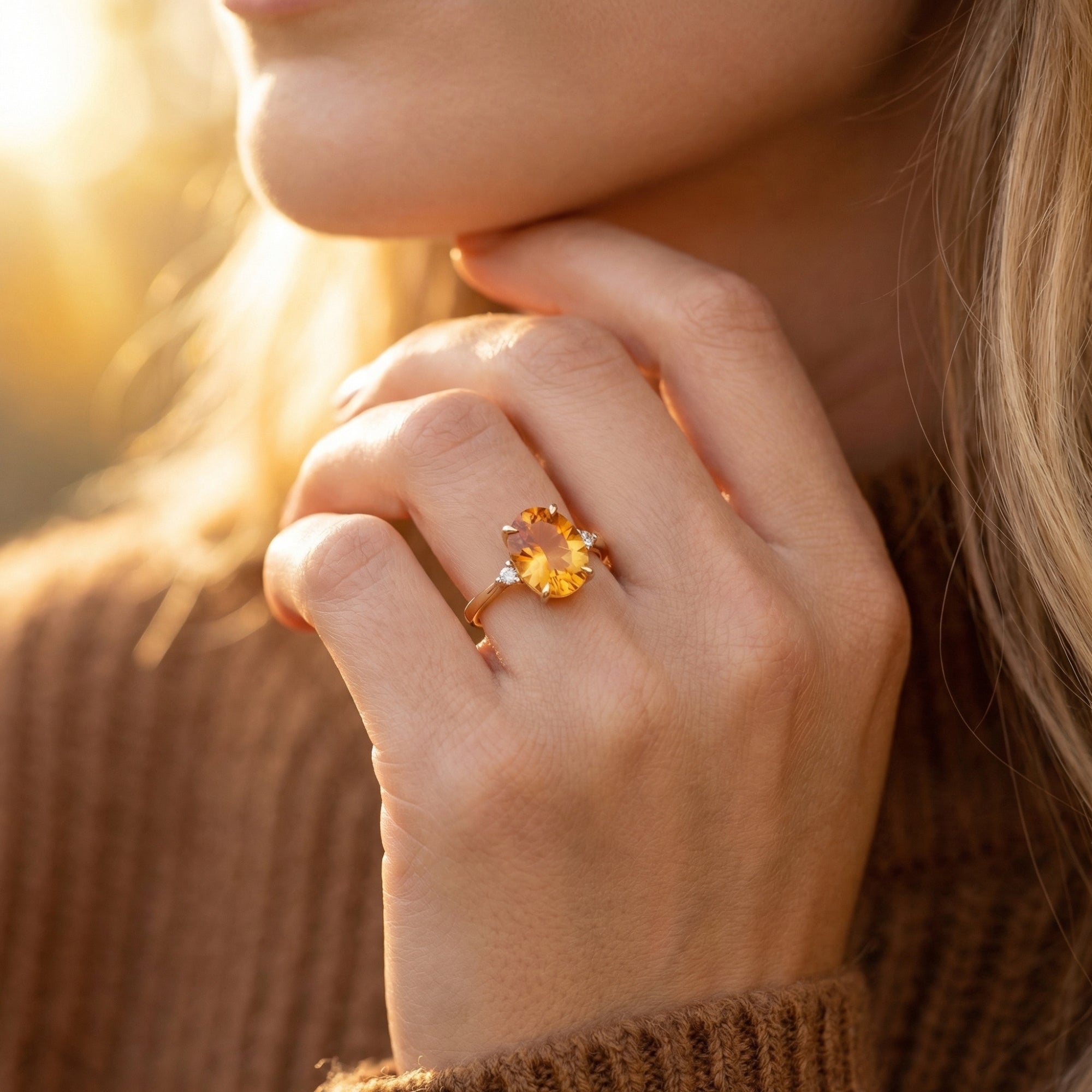 Woman wearing the 18K yellow gold oval-cut natural citrine ring on her finger in warm outdoor light.