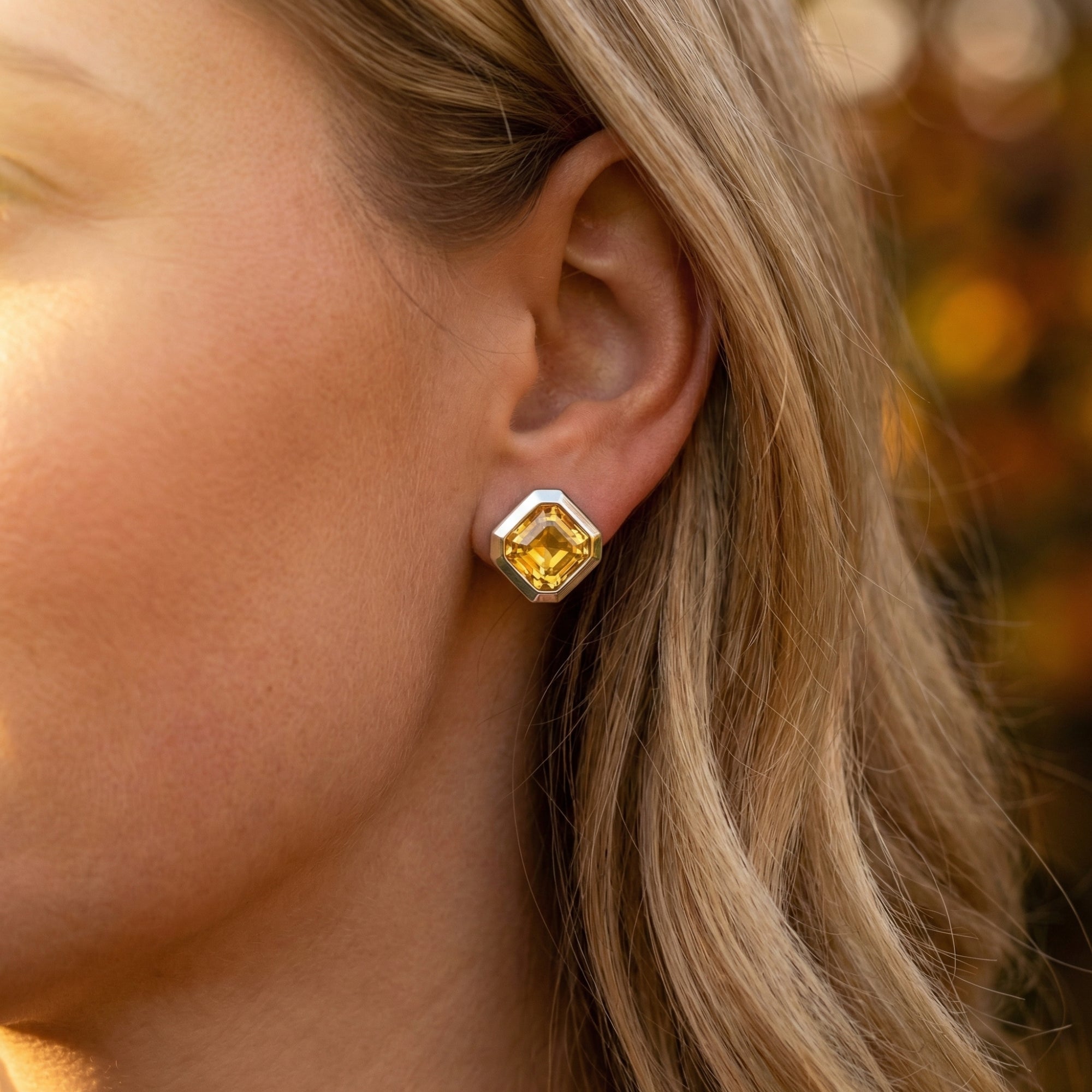 Side view of a woman wearing a Leonie natural citrine stud earring in white gold, showcasing its size on the ear.