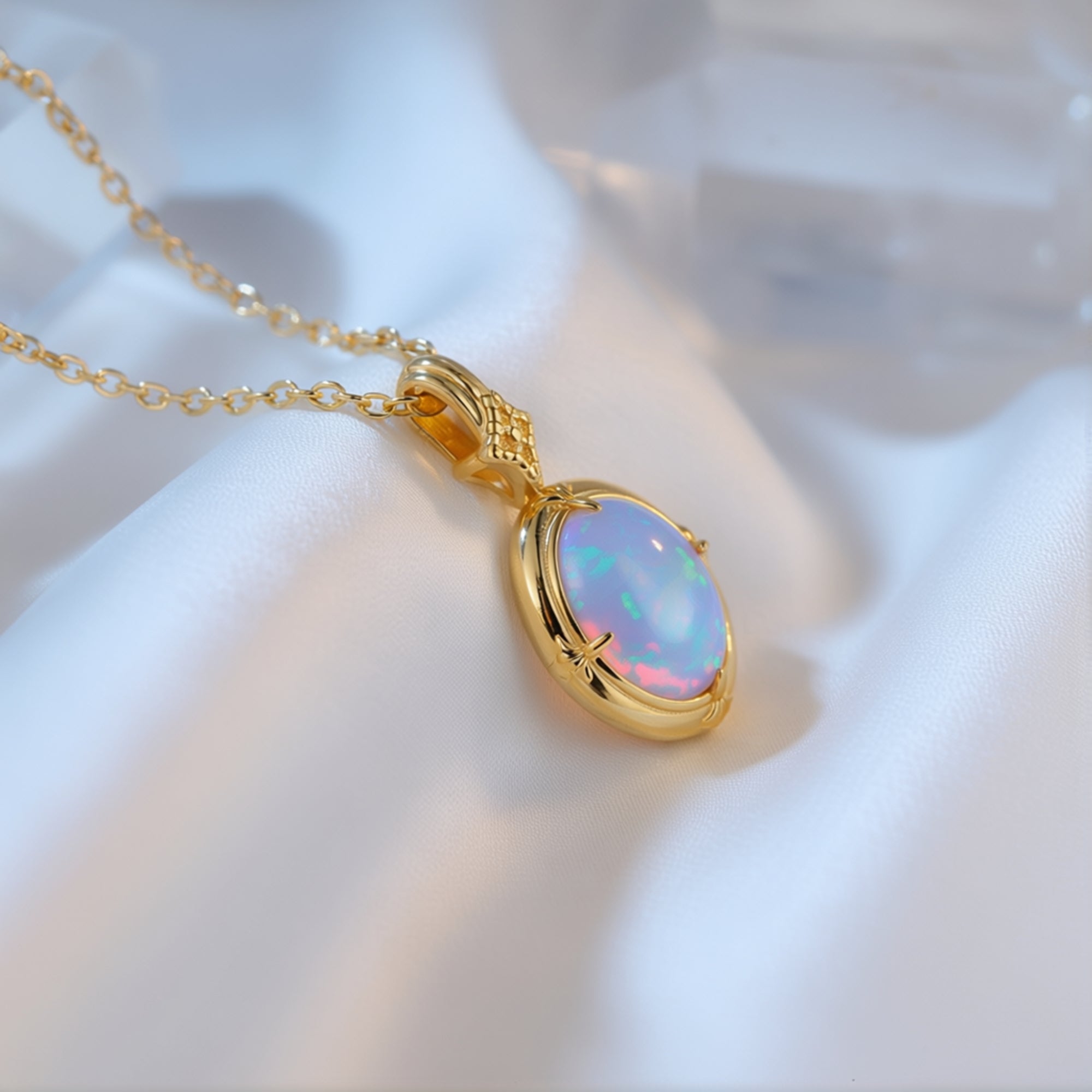 Macro view of the gold-tone oval white opal pendant on white fabric highlighting the stone's fire.