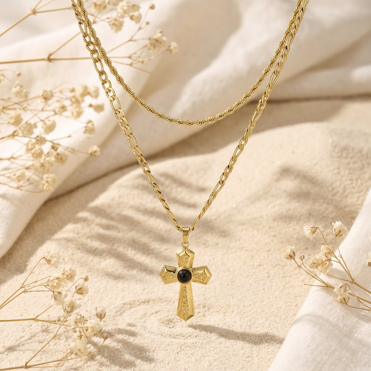 Suspended gold-tone layered necklace featuring an ornate cross pendant with a dark center cabochon.