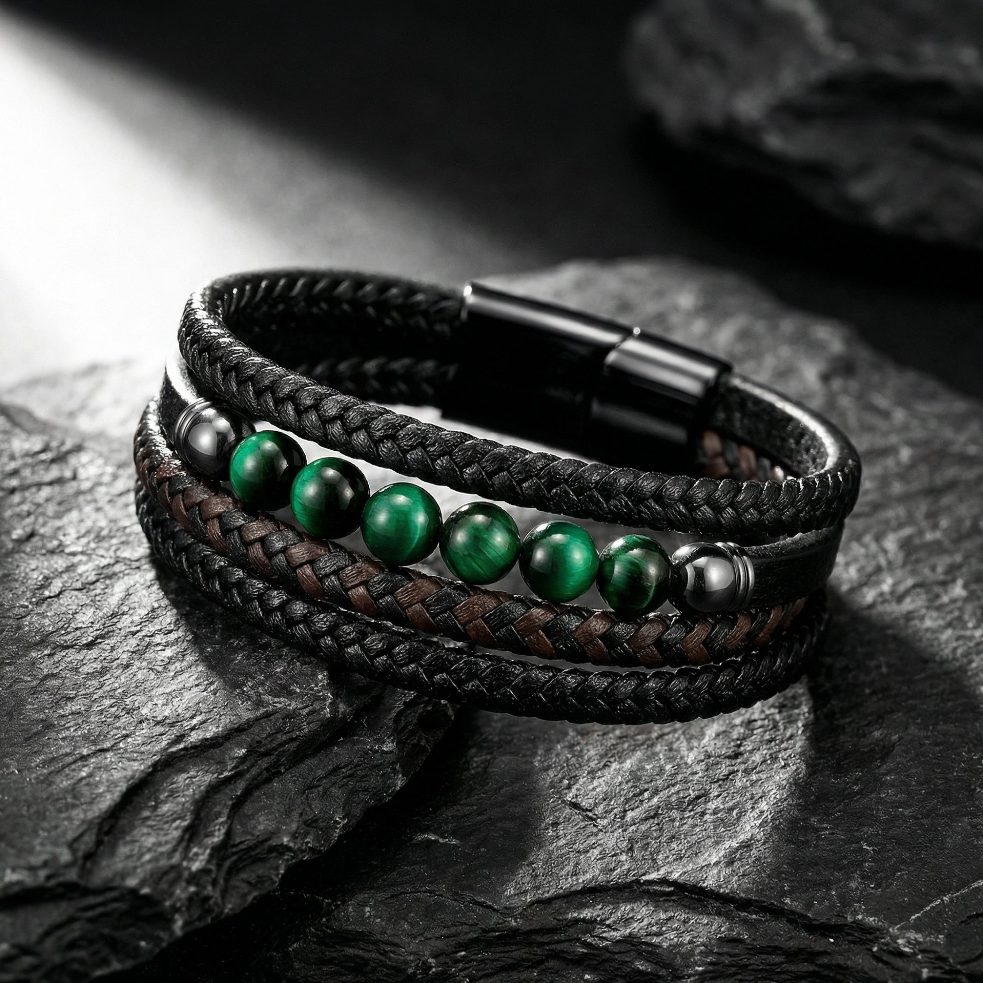 Macro view of green tiger eye beads and black braided leather strands on a men's stainless steel bracelet.