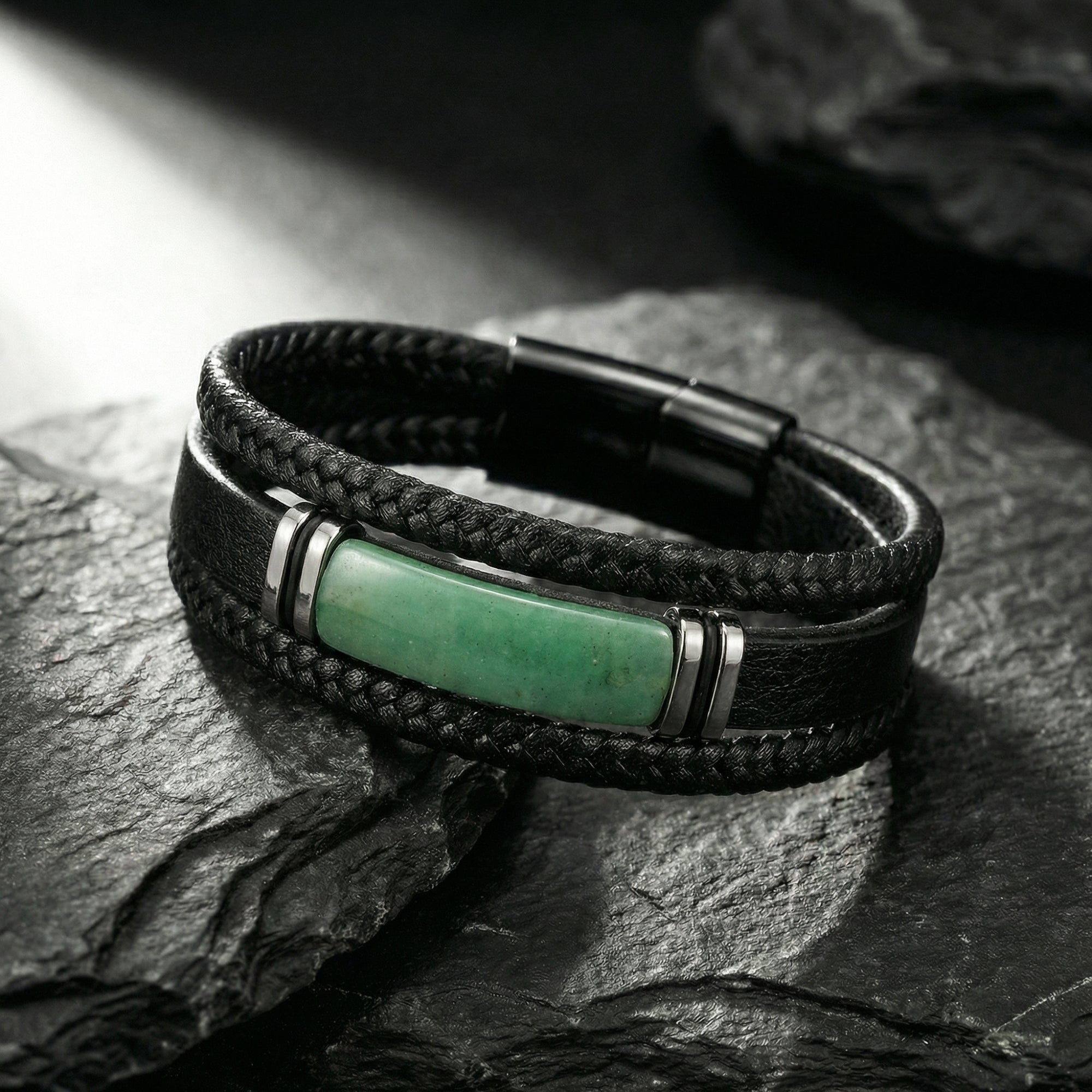 Front view of a men's black braided leather bracelet with a green stone centerpiece and 316L steel accents on stone.