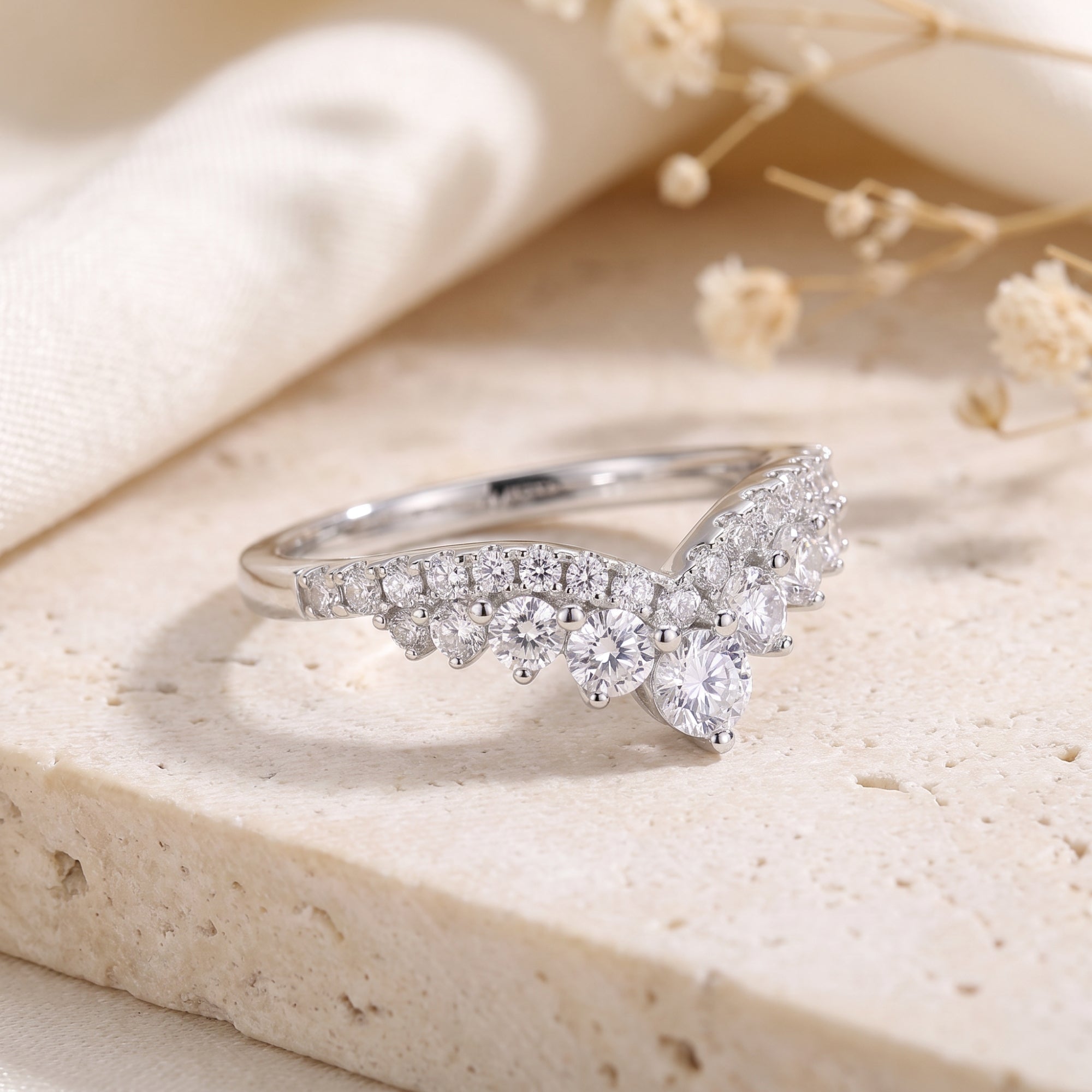 Close-up of a silver wishbone ring featuring precision-cut cubic zirconia stones on a textured base.